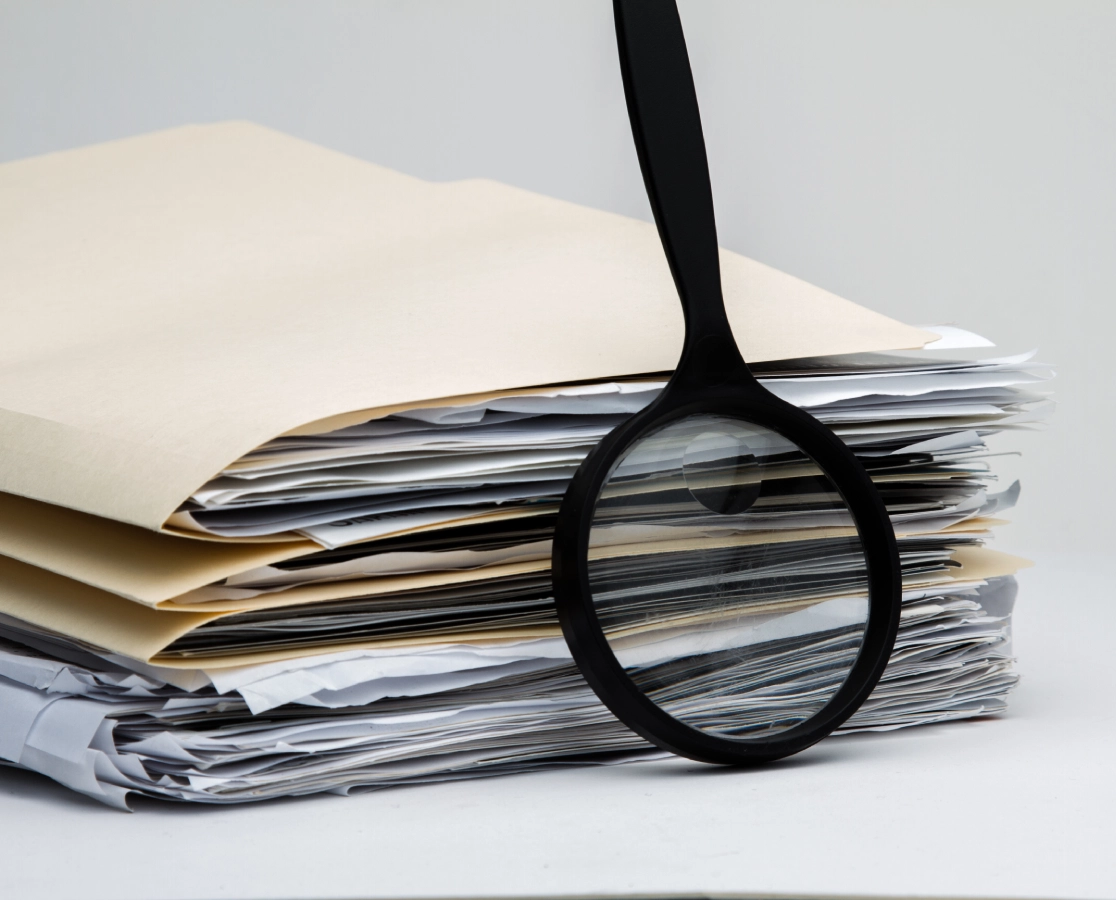 Magnifying glass on stack of papers.